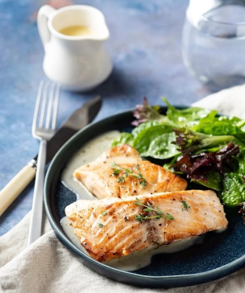 Saumon cuit sur une plaque noire avec une salade d'accompagnement.