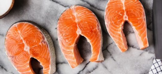 3 pavés de saumon sur une planche à découper en marbre