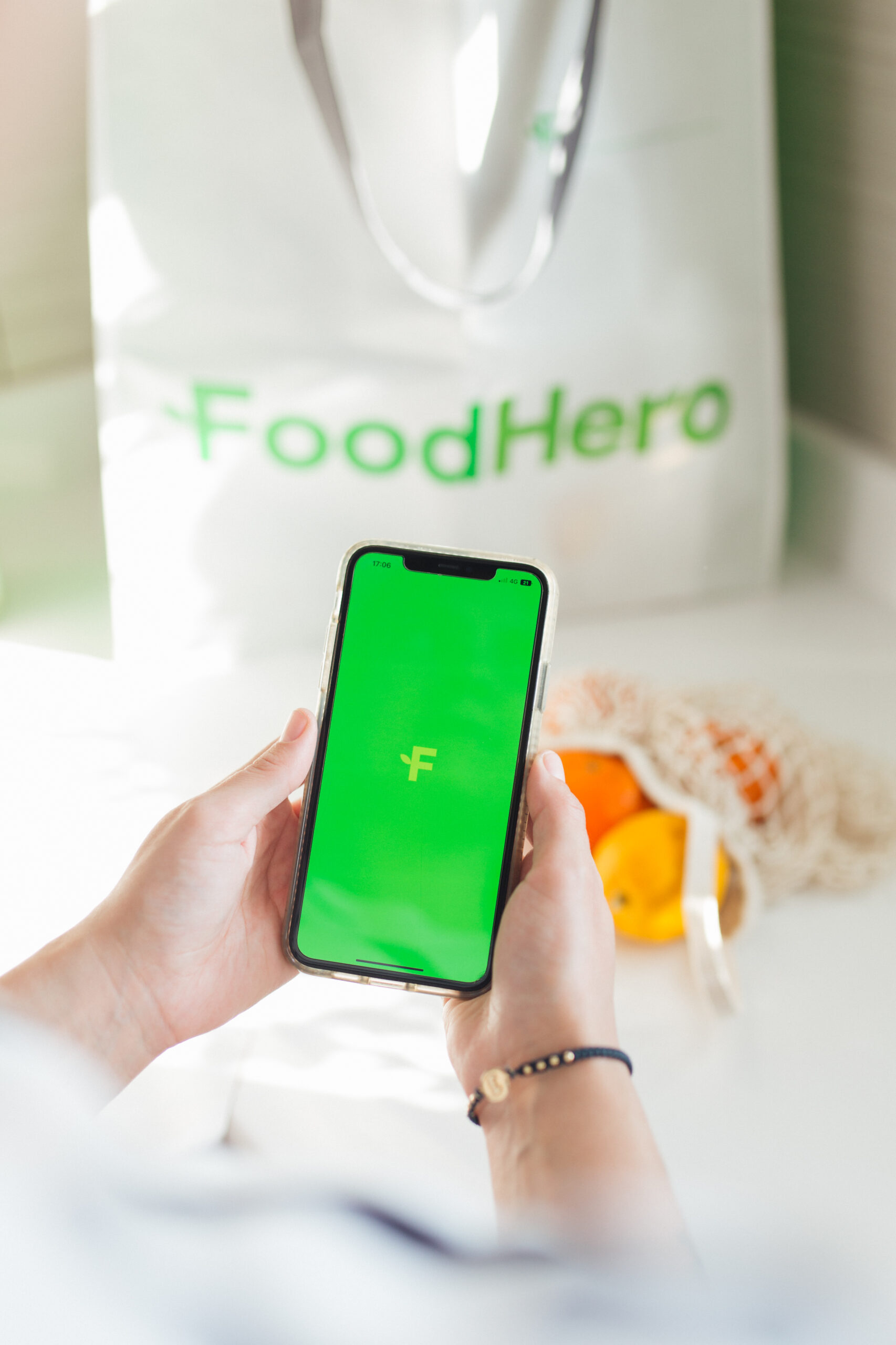 Téléphone avec le logo FoodHero et un sac de courses FoodHero en arrière-plan